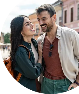 A smiling couple standing outdoors in casual attire, engaged in conversation.