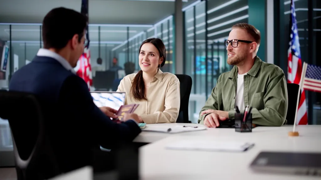 Three individuals engaged in a discussion at a modern office, with American flags displayed.